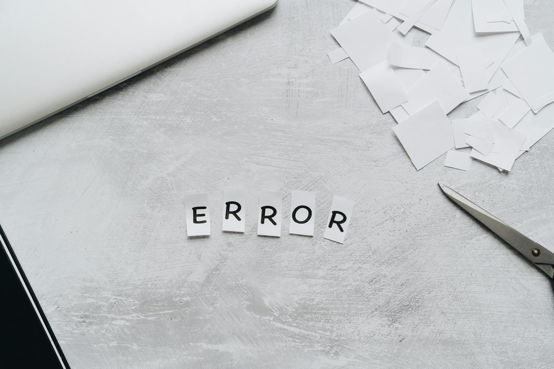 Creative concept showing the word 'error' with cut out letters on a table with scissors and paper.