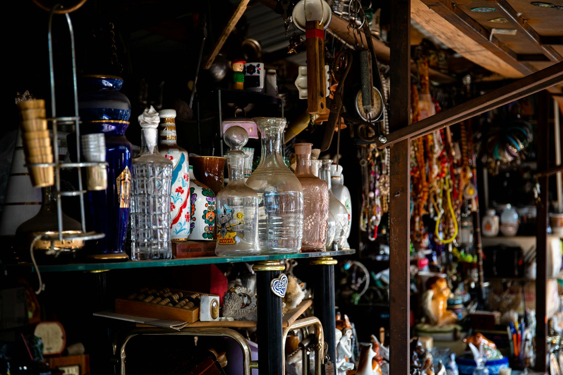 Eclectic assortment of vintage glassware and decor items displayed on a shelf in an antique store.