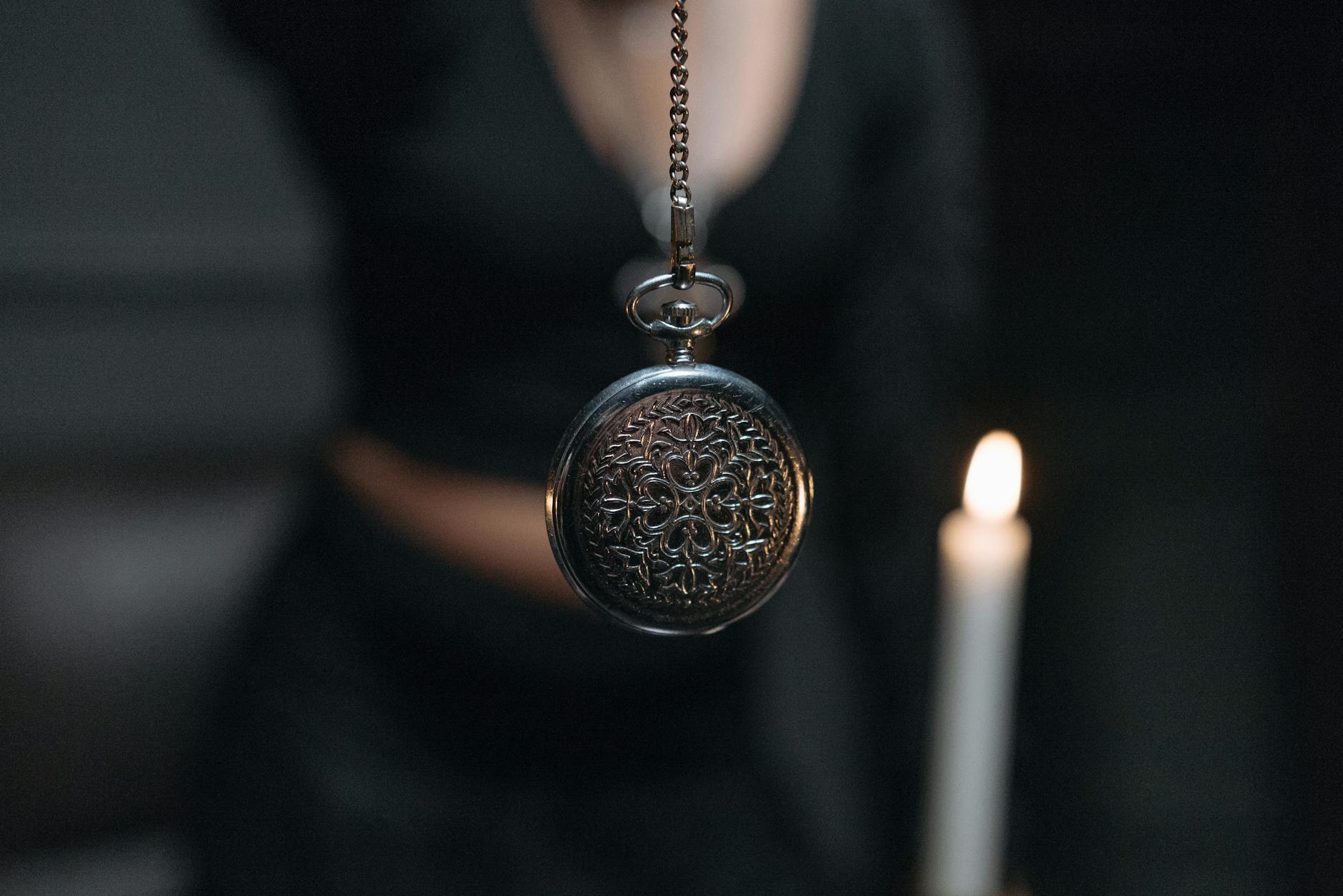 Close-up of a mystical silver pendant with candlelight, evoking a sense of spiritualism.