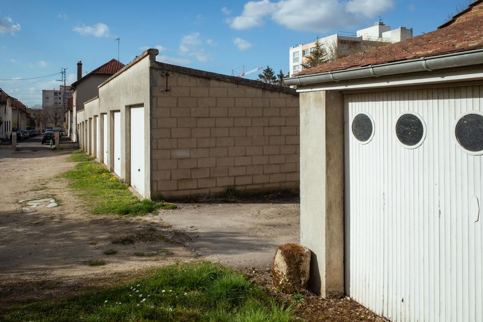 Street view of garages and urban buildings in Compiègne, Hauts-de-France, on a sunny day.