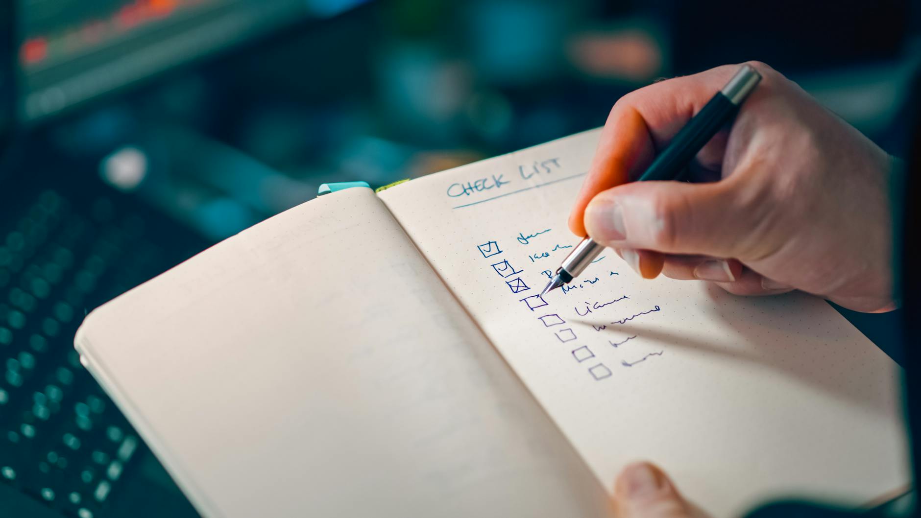 Close-up of a hand writing in a notebook with a checklist for effective task management.