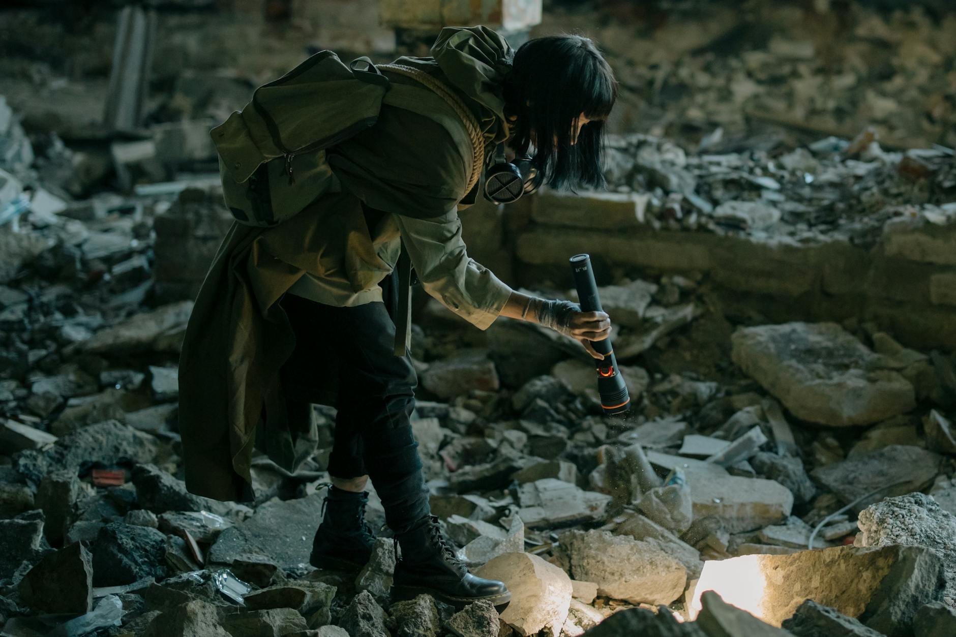 Person exploring an abandoned urban ruin with a flashlight, amidst debris and decay.