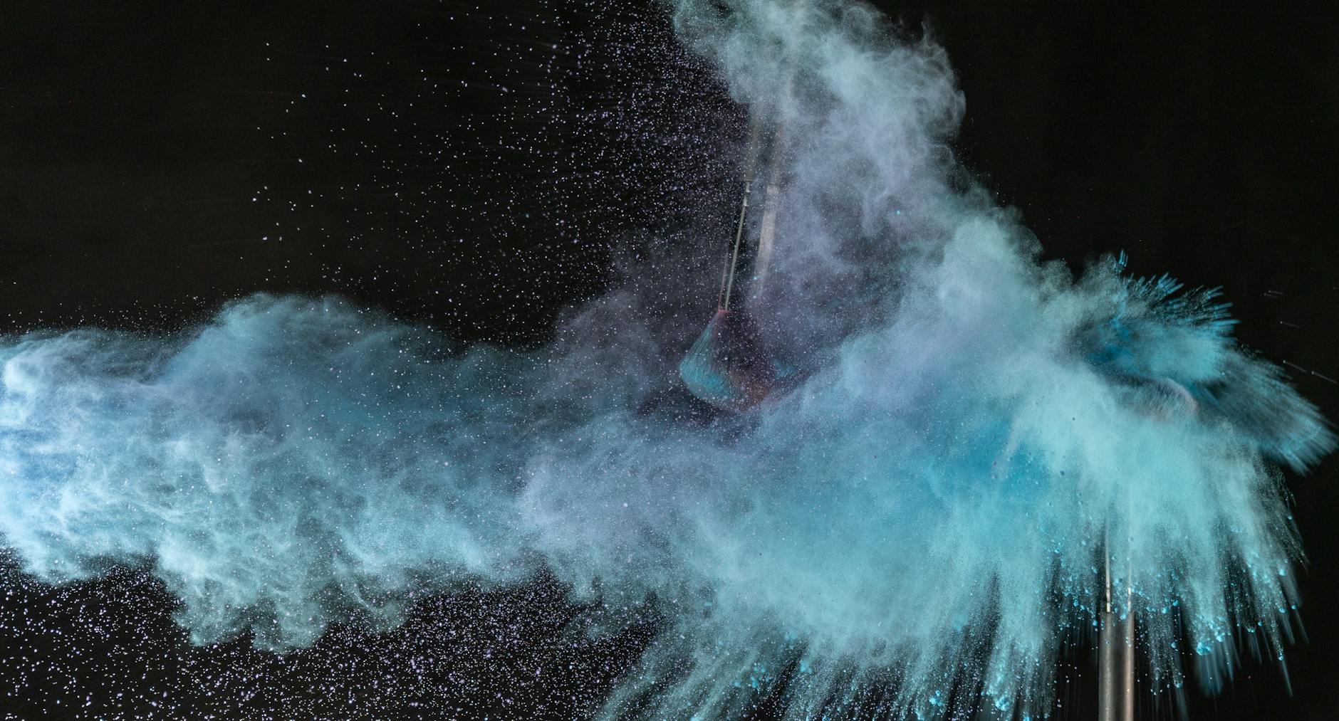 Explosive splash of blue powder creating vibrant cloud effect against black background.