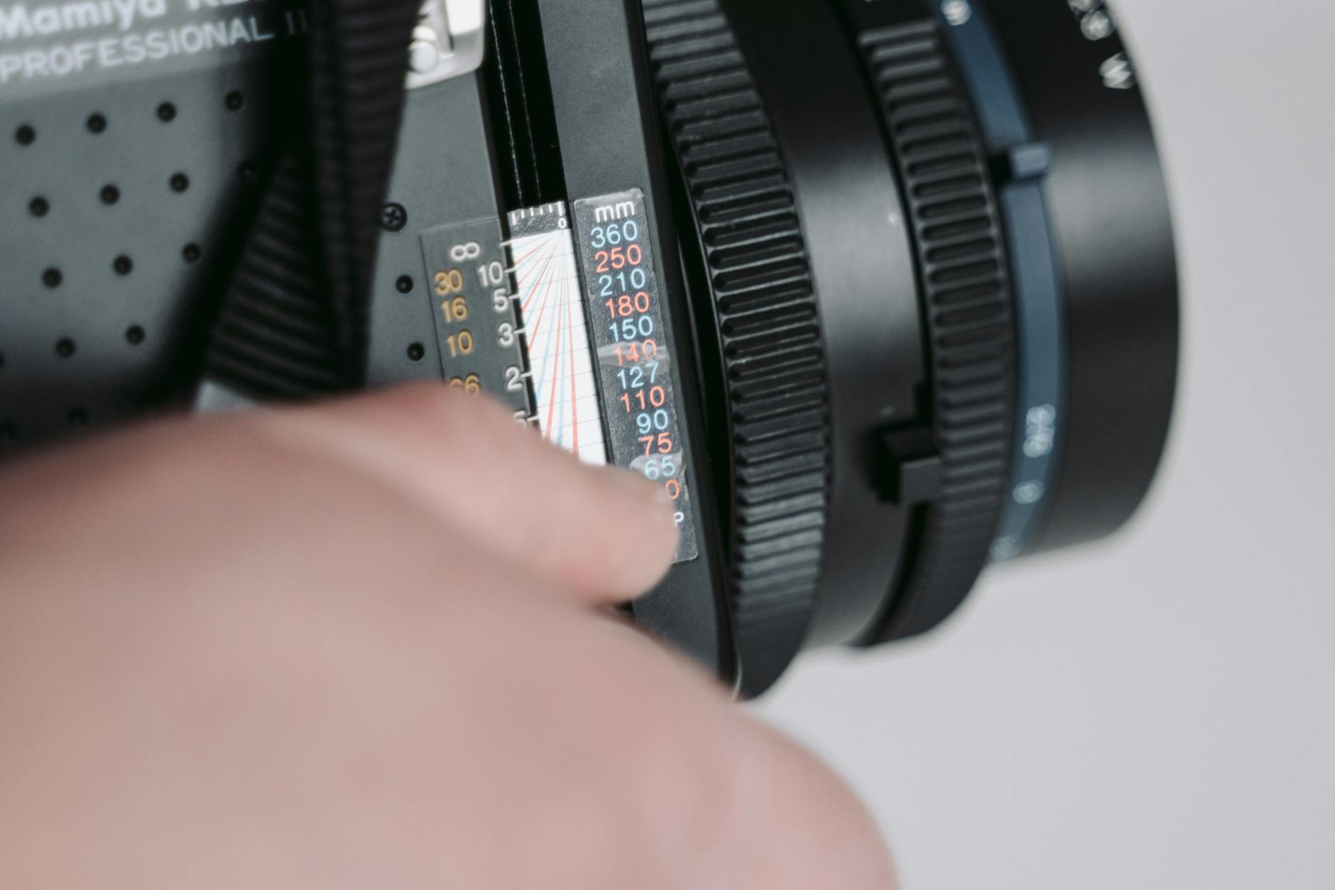 Macro shot of hand adjusting settings on a professional camera lens.